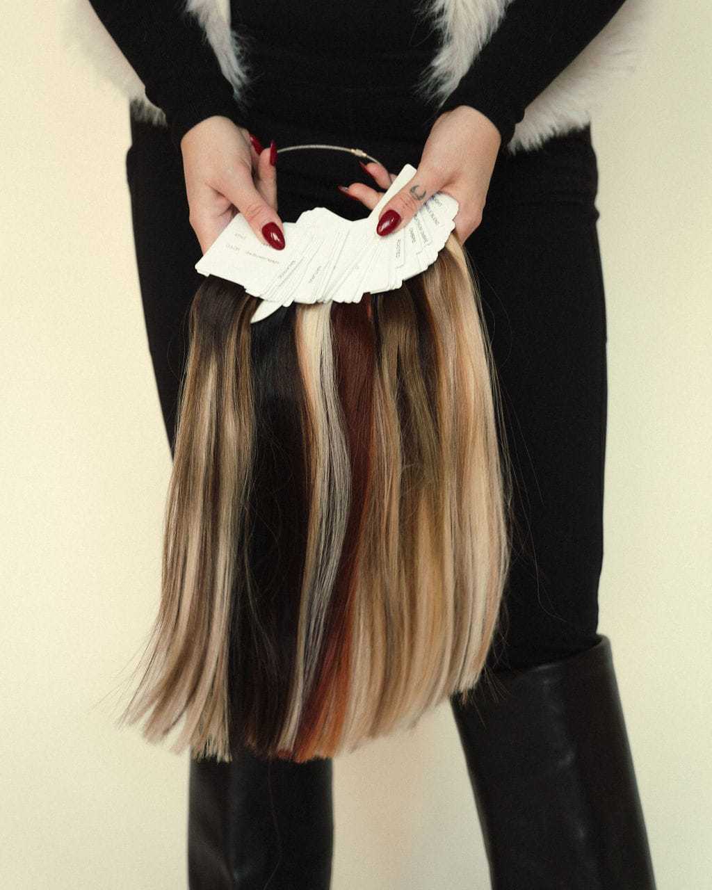 Person holding a ring of hair color samples displaying various shades and highlights.